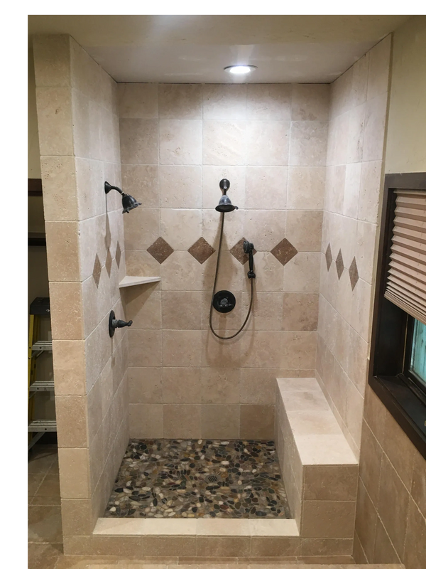 Modern tiled shower with pebble floor and built-in bench.