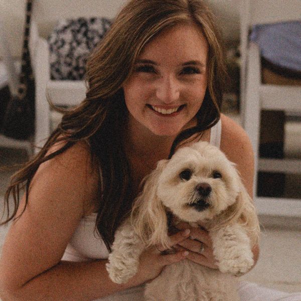 Woman smiling and holding a small fluffy dog.