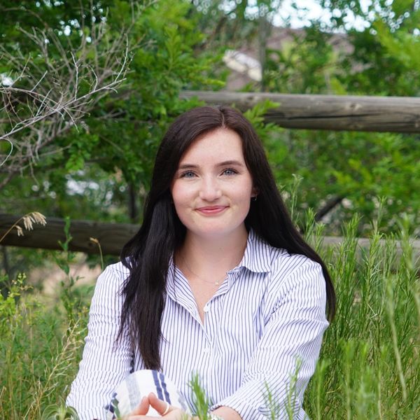 Woman smiling in a field with greenery.