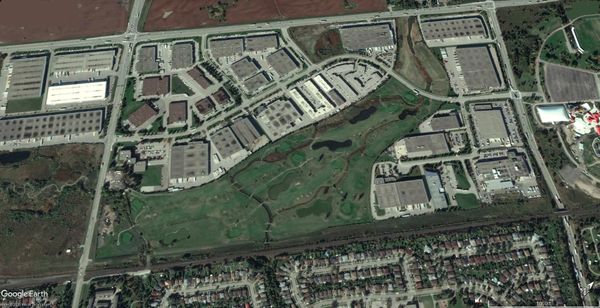 Aerial view of a commercial area with a golf course in the center.