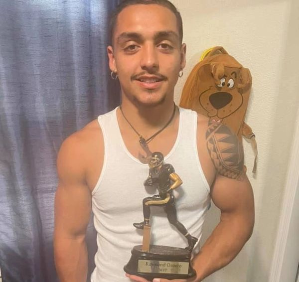 Young man holding a football MVP trophy, smiling.