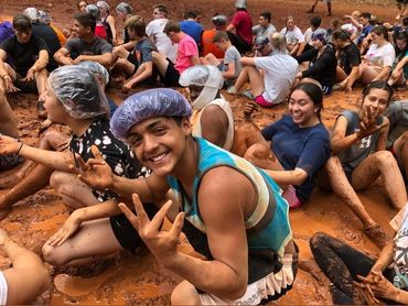 Group of people enjoying a muddy outdoor activity together.