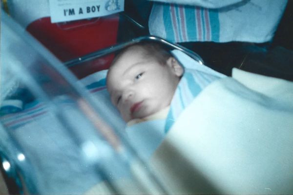 Newborn baby boy wrapped in a hospital blanket.