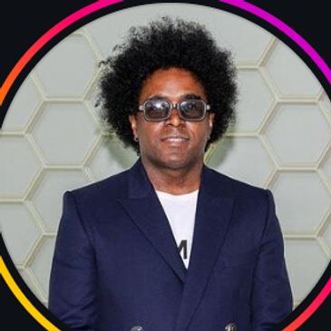 Man with sunglasses and afro hairstyle in navy suit.