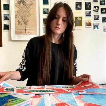 A woman with long hair arranging colorful cards on a table.