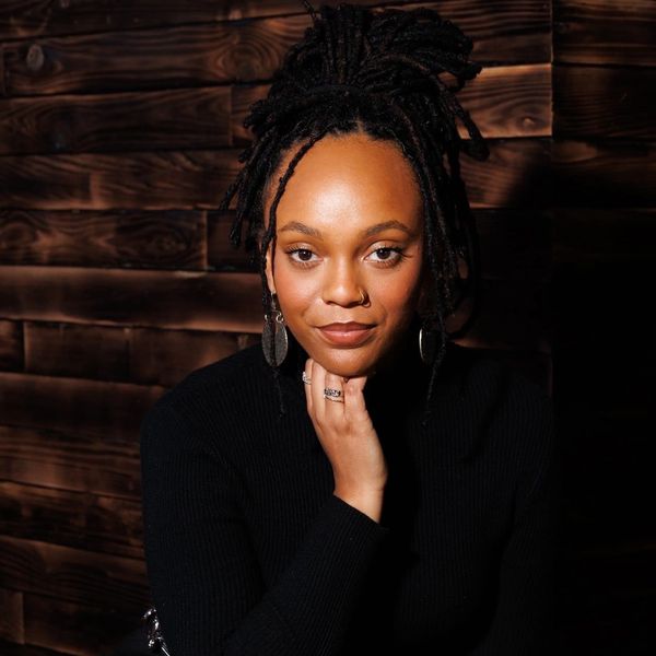 Portrait of a woman with dreadlocks against a wooden wall.