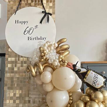 60th birthday balloon decoration with gold and white theme.