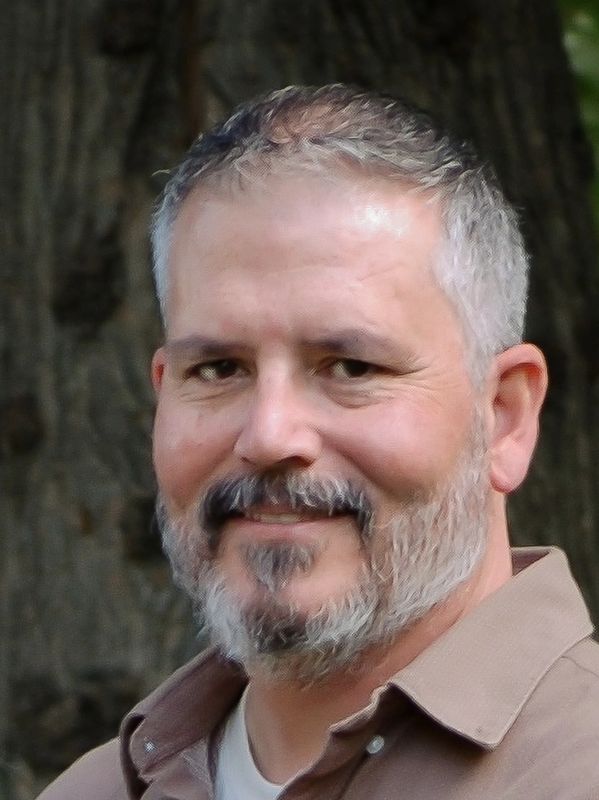 Smiling middle-aged man with gray beard and short hair.