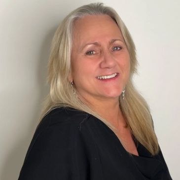 Smiling woman with long blonde hair in black top against a plain background.