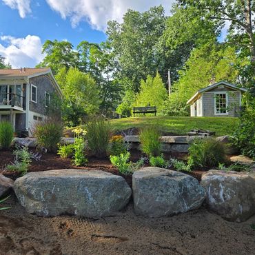 A lush backyard garden with large rocks and greenery.