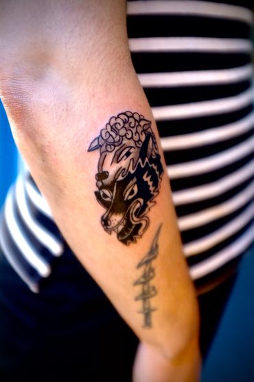 Tattoo of a wolf wearing a sheep's head on an arm.