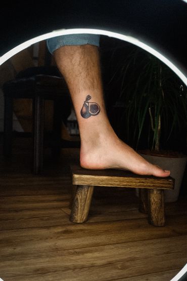 Tattoo of a fig fruit on a person's ankle.