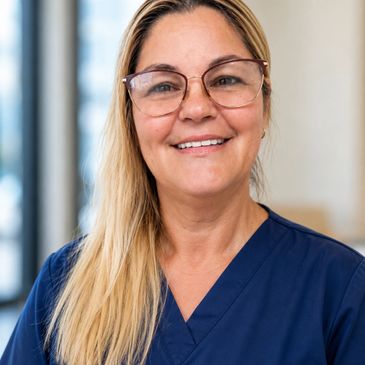Smiling woman in blue medical scrubs and glasses.