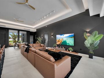 Modern living room with brown leather sofas and black accent wall.
