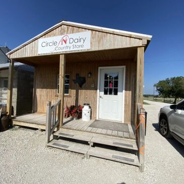 Wooden country store building with a white door and sign.