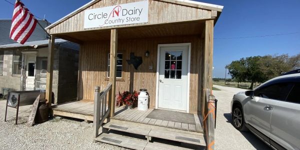 Wooden country store building with a white door and sign.