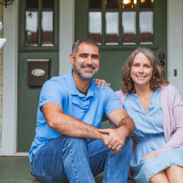 Smiling couple sitting on front steps of a house.