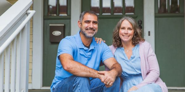 Smiling couple sitting on front steps of a house.