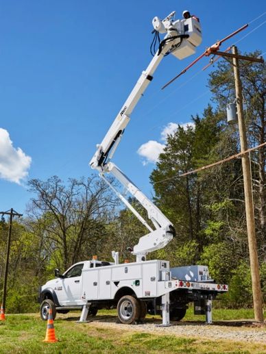 Boom truck with bucket and person working power lines 