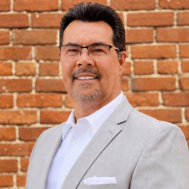 Man in light gray suit jacket and glasses.