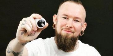 Smiling man showing a small object.