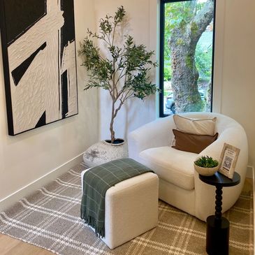White Arm Chair in a hallway with a small side table and foot rest.