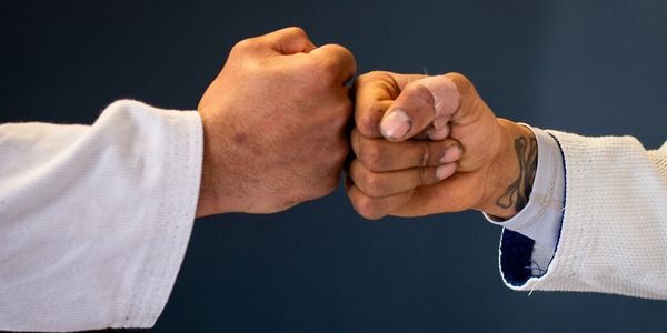 Two fists bumping together signifying the unity and camaraderie of our Jiu Jitsu community.