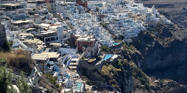 White buildings densely packed on a cliffside under a clear blue sky.