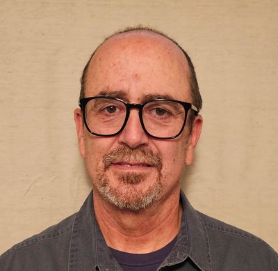 Middle-aged man with glasses and a goatee smiling slightly.