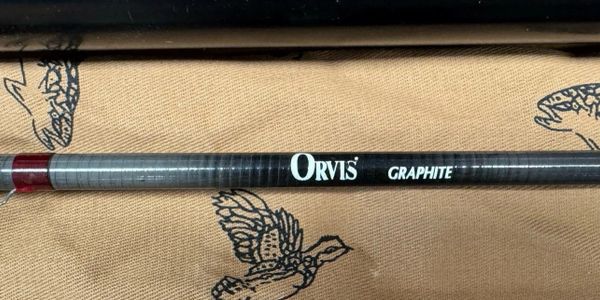 Close-up of an Orvis Graphite fishing rod on a patterned fabric.