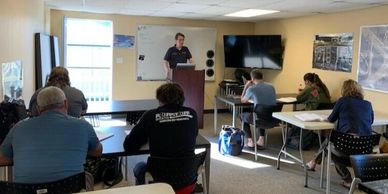 A man giving a presentation to a small audience in a classroom setting.