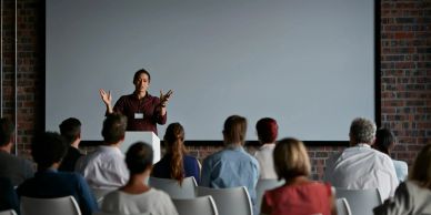 A speaker presenting to an audience in a conference room.