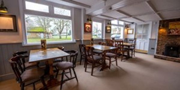 Cozy restaurant dining area with wooden tables and chairs beside large windows.