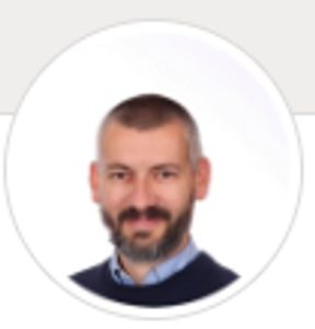 Profile photo of a smiling man with a beard and short hair.