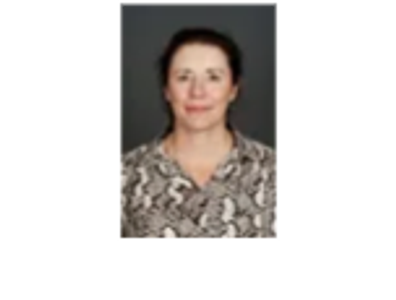 Portrait of a woman with a neutral expression against a dark background.