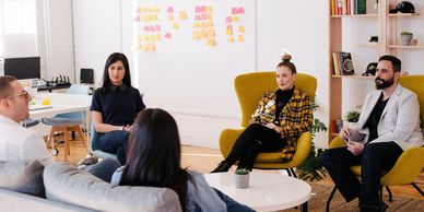 Group of five people sitting in an office having a meeting.