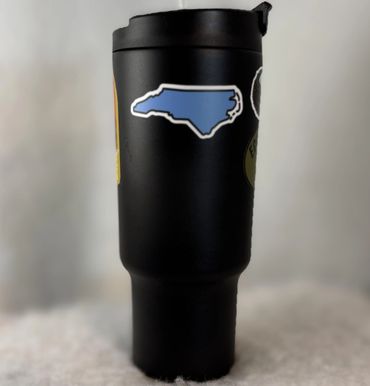 Black travel mug with a blue North Carolina sticker on it.