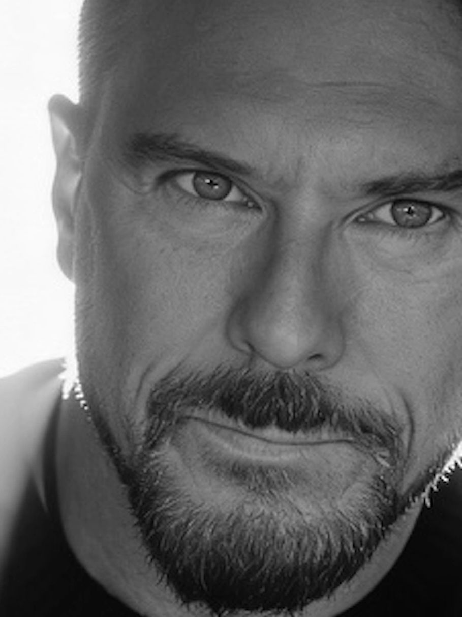 Close-up black and white portrait of a man with a beard and intense gaze.