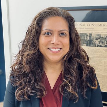 Smiling woman with long curly hair in professional attire.