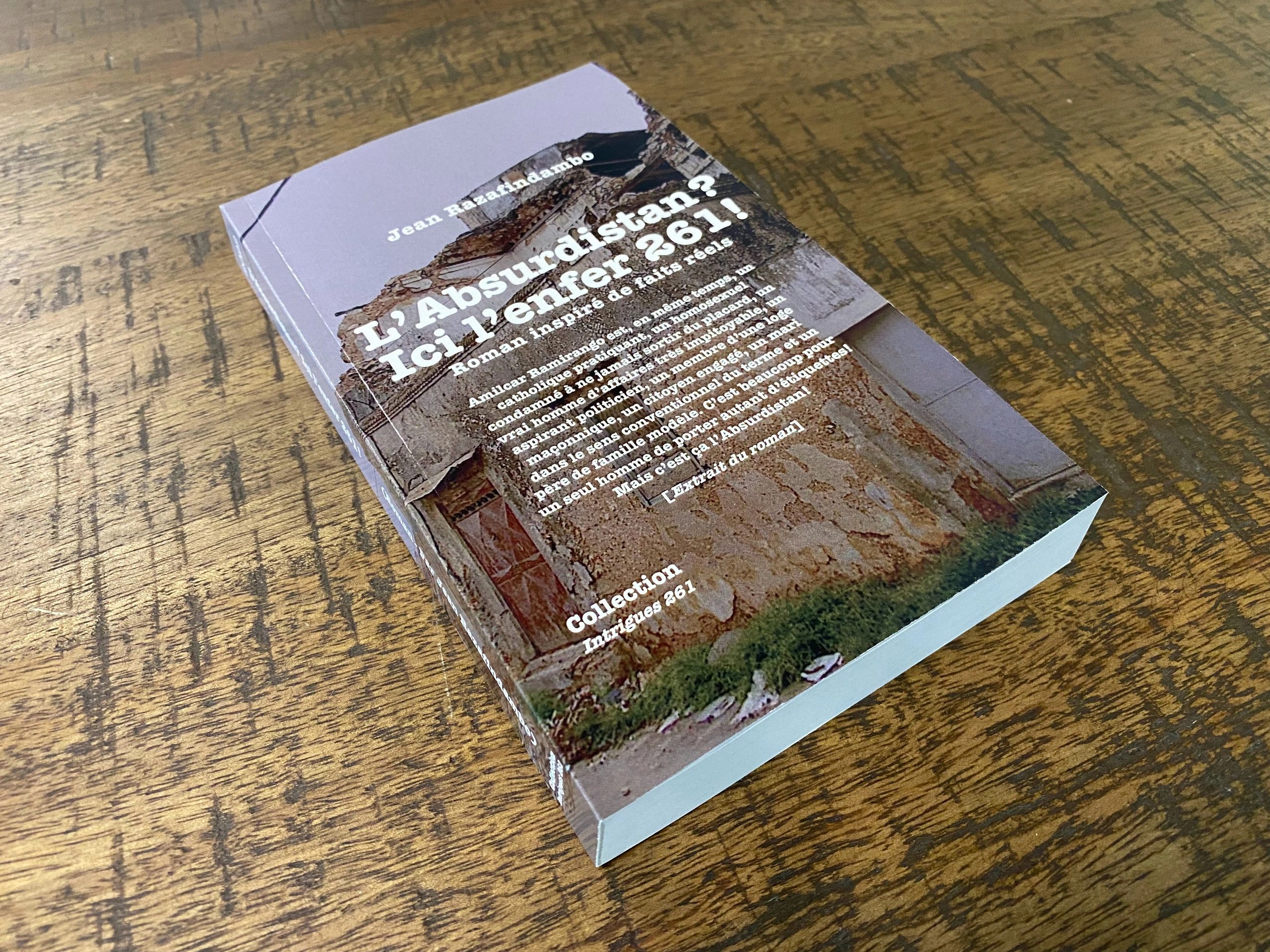 Book titled "L'Absurdistan? Ici l'enfer 261!" by Jean Razafindambo on a wooden table.