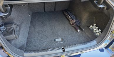 Open car trunk with an umbrella and water bottles inside.