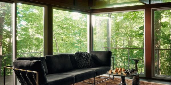 Modern living room with large windows and forest view.