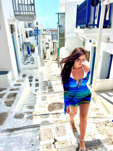 Woman walking on a sunny white stone street in a coastal town.