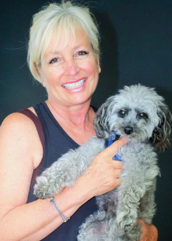 Smiling woman holding a small gray dog.