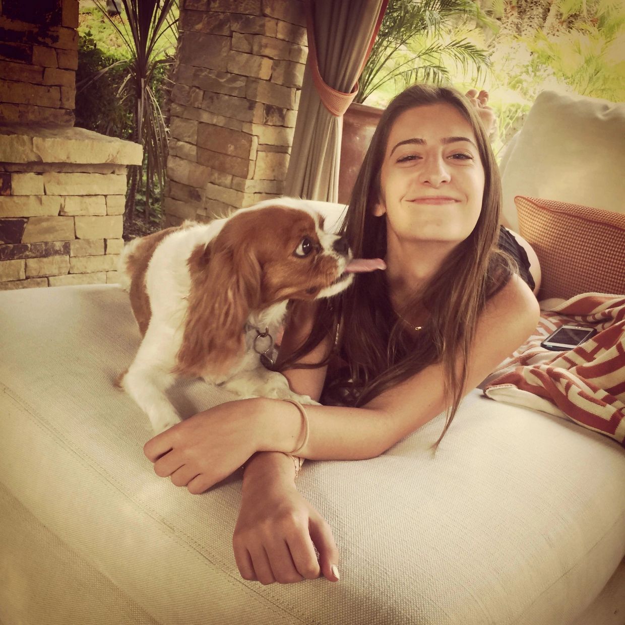 A dog licking a woman's face indoors.