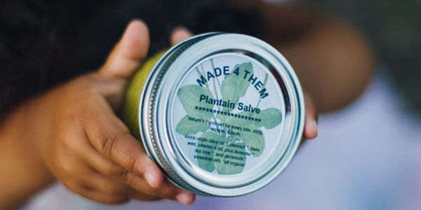 Daughter holding a 4 oz jar of Plantain Salve