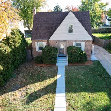 Cozy brick house with a steep roof and front shrubs.