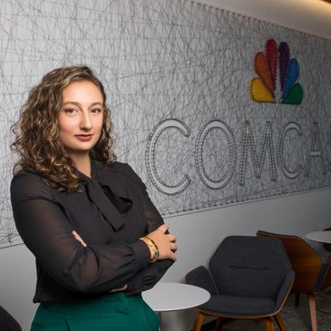 Former University of West Georgia student Nadia Aghaie stands in front of the Comcast logo.
