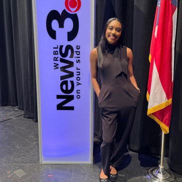Former University of West Georgia student Simone Gibson standing in front of the WRBL News 3 sign.
