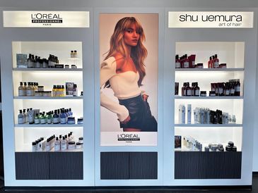 L'Oréal and Shu Uemura hair products display with a model poster.